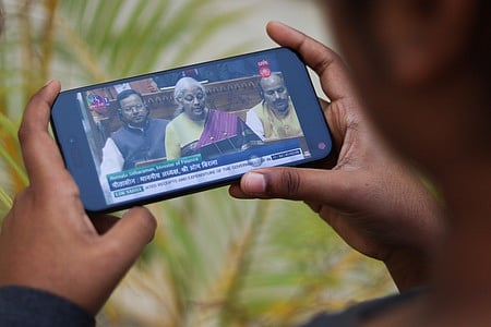 An office-goer watching the live telecast of the Union Budget 2026 in Bengaluru on Sunday.