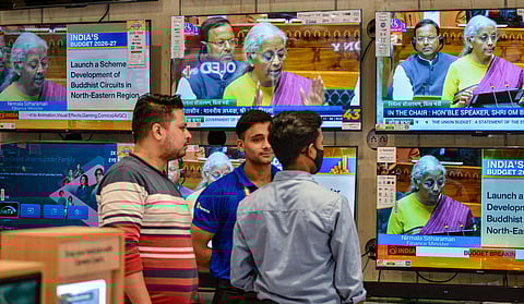 People watch the presentation of the Union Budget 2026-27 by Finance Minister Nirmala Sitharaman, virtually, at an electronics store, in New Delhi, Sunday, Feb. 1, 2026.
