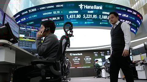 A currency trader talks on the phone near a screen showing the Korea Composite Stock Price Index (KOSPI), top center, and the foreign exchange rate between U.S. dollar and South Korean won, top center left, at the foreign exchange dealing room of the Hana Bank headquarters in Seoul, South Korea, Friday, Jan. 30, 2026