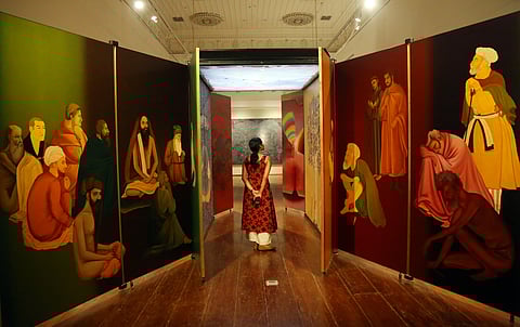 A visitor walks through 'Kaavad' by Gulammohammed Sheikh at Durbar Hall in Kochi 