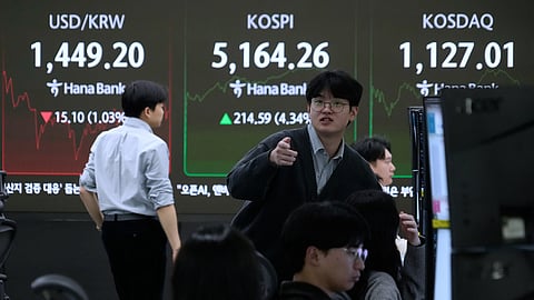 Currency traders work near a screen showing the Korea Composite Stock Price Index (KOSPI), top center, and the foreign exchange rate between U.S. dollar and South Korean won, top left, at the foreign exchange dealing room of the Hana Bank headquarters in Seoul, South Korea, Tuesday, Feb. 3, 2026.