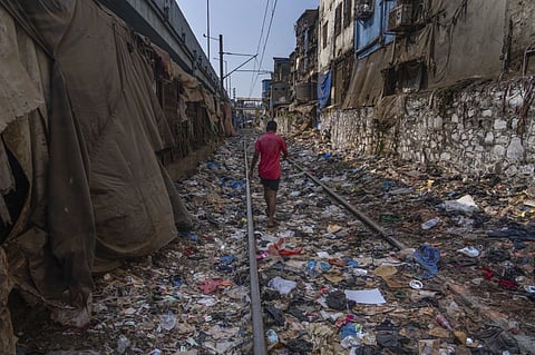 A man walks on a railway track littered with plastic and other waste materials on Earth Day in Mumbai