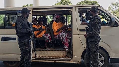 Security officers stand guard next to a bus carrying freed worshippers at the Government House in Kaduna on February 5, 2026.
