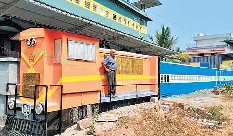The house of T Damodaran modelled after a train coach. The wall is in the shape 
of a rake hauled by an orange liveried ALCO locomotive