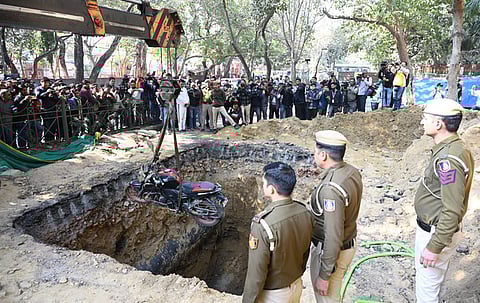 The bike of a motorcyclist who plunged into an uncovered pit dug for construction work being lifted out at Janakpuri, New Delhi