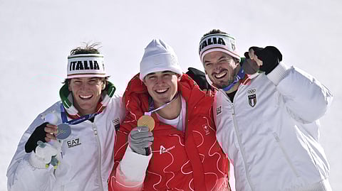 Gold medallist Switzerland's Franjo von Allmen (C), silver medallist Italy's Giovanni Franzoni (L) and bronze medallist Italy's Dominik Paris (R) pose on the podium after the men's downhill alpine skiing event during the Milano Cortina 2026 Winter Olympic Games at the Stelvio Ski Centre in Bormio (Valtellina) on February 7, 2026. 