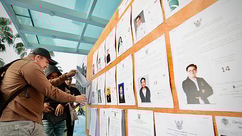 Voters look at candidates listed on a display board before entering a voting station for the general election in Bangkok on Sunday, Feb. 8, 2026.