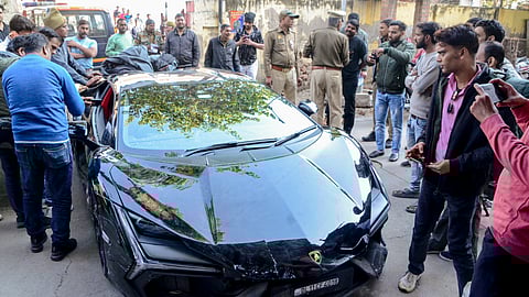People gather around a Lamborghini car which collided with a rickshaw, injuring three people, in Kanpur, Sunday, Feb. 8, 2026.