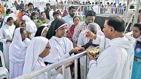 A catholic priest offers bread to the nuns during the day one of three day festival at Gunadala Mother Mary Shrine in Vijayawada.