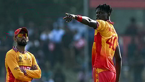 Zimbabwe's captain Sikandar Raza (L) speaks with teammate Blessing Muzarabani during the 2026 ICC Men's T20 Cricket World Cup group stage match between Zimbabwe and Oman.
