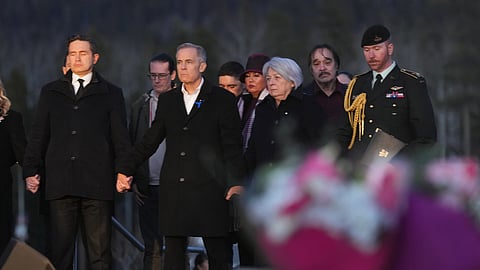 From left to right, Leader of the Official Opposition of Canada Pierre Poilievre, Prime Minister Mark Carney and Governor General of Canada, Mary Simon join hands while attending a vigil for the victims of a mass shooting, in Tumbler Ridge, B.C., Friday, Feb. 13, 2026.