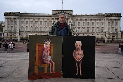 Artist Kaya Mar poses with the newest edition of his paintings for the media in front of Buckingham Palace, London, Friday, Feb. 20, 2026, after Andrew Mountbatten-Windsor was arrested and held for hours by British police on suspicion of misconduct in public office related to his links to Jeffrey Epstein.