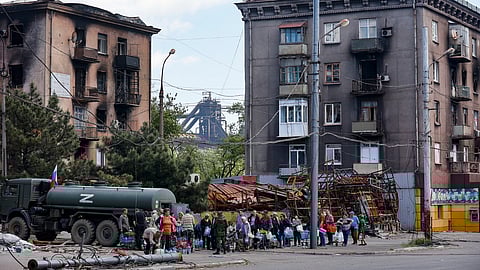 Civilians gather to receive drinking water distributed by the Russian Emergency Situations Ministry in Mariupol on May 27, 2022, after the seaside city in eastern Ukraine fell to Moscow's troops.