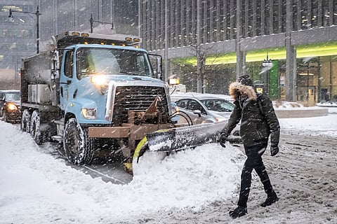 A man crosses Wacker Drive in front of a waiting city snowplow in Chicago