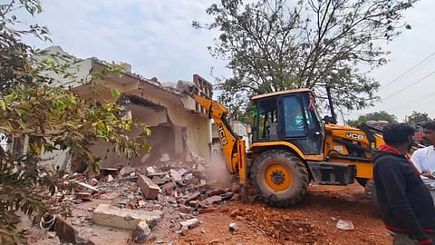 A bulldozer razes a house in Khammam on Tuesday.
