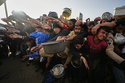 Displaced Palestinian struggle to receive donated food for iftar, the fast-breaking meal, on the first day of the Muslim holy month of Ramadan at a community kitchen in Khan Younis, Gaza Strip, Wednesday, Feb. 18, 2026. 