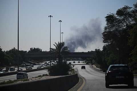 Motorists drive along a street as smoke rises from a reported Iranian strike in the area where the US Embassy is located in Kuwait City on March 2, 2026.