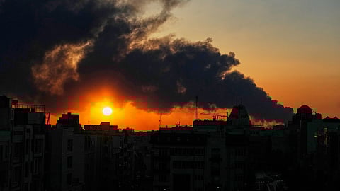 The sun sets behind a plume of smoke rising after a U.S.–Israeli military strike in Tehran, Iran, Tuesday, March 3, 2026.