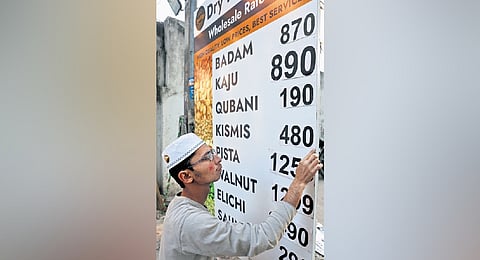 A shopkeeper updates a board displaying dry fruit prices in Hyderabad on Thursday