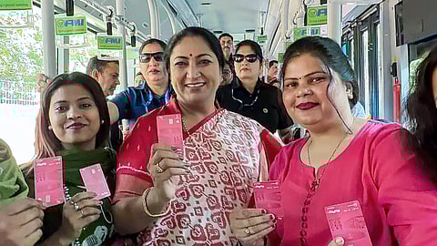 Delhi Chief Minister Rekha Gupta, with others, poses with a pink NCMC card as she travels in a DTC bus in New Delhi on Saturday, March 7, 2026.