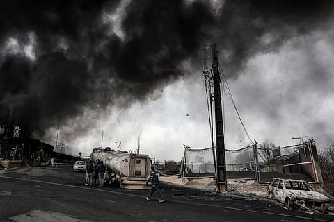 Dark smoke clouds engulf destroyed vehicles near an ongoing fire following an overnight airstrike on the Shahran oil refinery in northwestern Tehran on March 8, 2026.