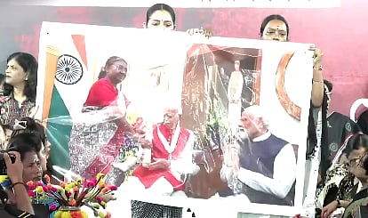 TMC cadre hold up a banner with a picture of the President standing while the PM and BJP leader LK Advani are seated.