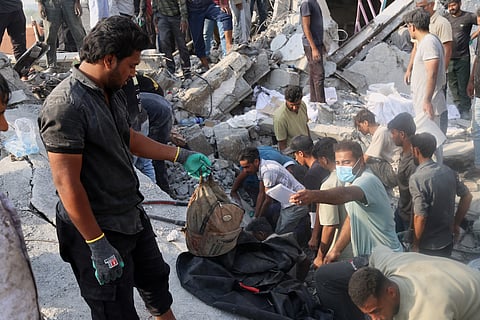 A man hold a children's backpack as rescue workers and residents search through the rubble in the aftermath of what Iranian officials said was an Israeli-U.S. strike on a girls' elementary school in Minab, Iran, Saturday, Feb. 28, 2026.