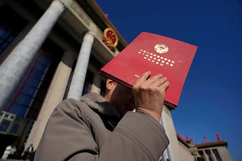 A delegate holds up a red folder as she leaves after the closing ceremony of the Chinese People's Political Consultative Conference (CPPCC), in Beijing, Wednesday, March 11, 2026.