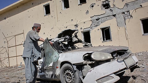 A man inspects a car damaged after a Pakistani strike on a refugee camp in Takhta Pul district, Kandahar province, Afghanistan, Saturday, Feb. 28, 2026.