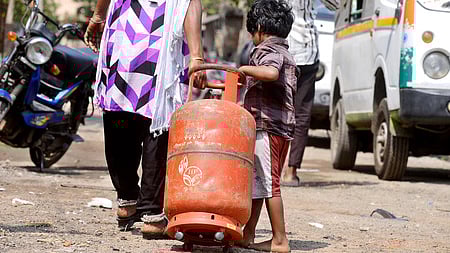 A young boy lends a helping hand to his mother as they roll an empty LPG cylinder to get it refilled in Chennai