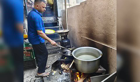 A cook uses firewood to prepare food at a hotel near BDA Complex at Koramangala due to shortage of Commercial LPG gas cylinders in Bengaluru.