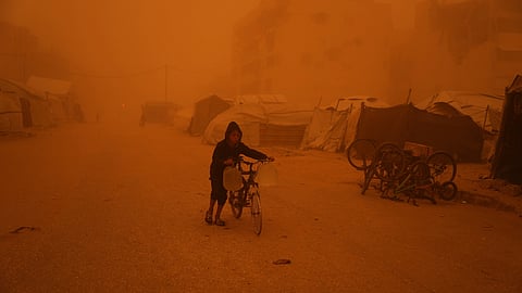 A boy pushes a bicycle carrying jerrycans of water through a sandstorm in Khan Younis, southern Gaza Strip, Saturday, March 14, 2026.