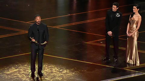 Michael B. Jordan accepts the award for actor in a leading role for "Sinners" during the Oscars on Sunday, March 15, 2026, at the Dolby Theatre in Los Angeles. Adrien Brody looks on from right.