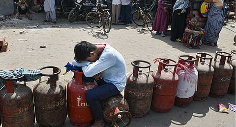 A child sits over an empty LPG cooking gas cylinder, as people arrive to avail refilled ones, amid a shortage linked to the ongoing West Asia conflict affecting the global energy supply chain, in Prayagraj, Tuesday, March 17, 2026.
