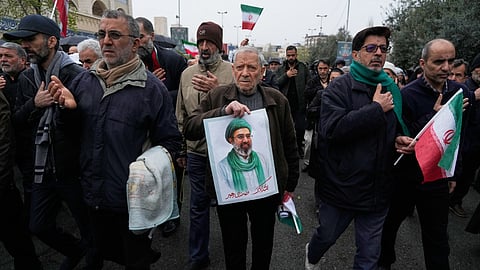 People mourn while one of them holds a poster of the Supreme Leader Ayatollah Mojtaba Khamenei during the funeral procession of Iran's intelligence minister Esmail Khatib and, according to Iranian officials, his wife and daughter, in Tehran, Iran, Friday, March 20, 2026. 