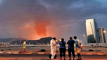 Foreign workers look at a tall plume of black smoke ascends following an explosion in the Fujairah industrial zone on March 3, 2026.