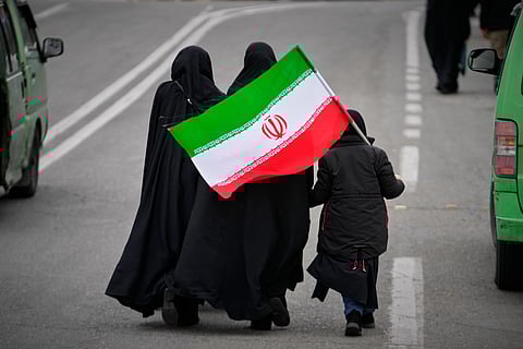 Two women and a child holding an Iranian flag walk toward the Imam Khomeini Grand Mosque to attend Friday prayers in Tehran, Iran, Friday, March 20, 2026.