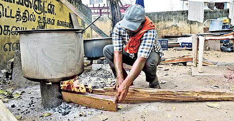 A food stall worker in Tiruchy deftly handles the intense heat of a traditional firewood stove.