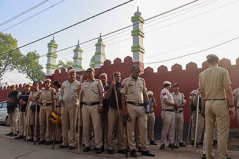 Police personnel stand guard as people arrive to offer prayers on the occassion of Eid al-Fitr, at Uttam Nagar in New Delhi, Saturday, March 21, 2026. Uttam Nagar, where a localised clash left a man dead and triggered communal tensions in the area, is observing Eid-ul-Fitr amid tight security.