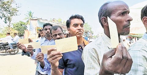 Farmers stand in queue in front of the main post office holding postcards in Bargarh