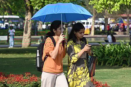 People seen covering their head with umbrella to protect themselves from heat  on a summer day at kartavya Path in New Delhi on Tuesday.