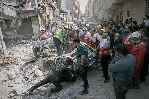 First responders inspect a destroyed car at the site of a residential building hit in an overnight strike during the U.S.-Israeli military campaign in Tabriz, East Azerbaijan Province, northwestern Iran, Tuesday, March 24, 2026.