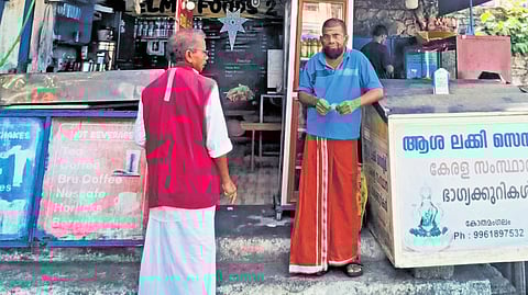 Tea stall owner Jagadish discussing politics, development with a lottery vendor near Kothamangalam