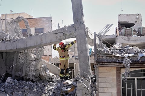 A first responder inspects the damaged structure of a residential building hit in an earlier U.S.-Israeli strike in Tehran, Friday, March 27, 2026.