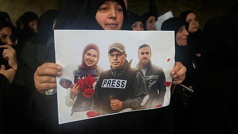 A woman holds a poster showing Hezbollah's Al-Manar TV correspondent Ali Shoeib, center, Al-Mayadeen TV reporter Fatima Ftouni, left, and cameraman Ali Ftouni during their funeral at a temporary cemetery in Dahiyeh, Beirut's southern suburbs, Beirut, Lebanon, Sunday, March 29, 2026. 