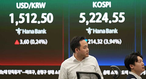 Dealers work near the screens showing the Korea Composite Stock Price Index (KOSPI), right, and the foreign exchange rate between U.S. dollar and South Korean won at a dealing room of Hana Bank in Seoul, South Korea, Monday, March 30, 2026.