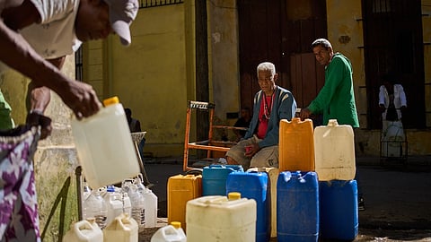 A man fill containers with potable water during a blackout in Havana, Sunday, March 22, 2026.