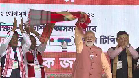 Prime Minister Narendra Modi waves a 'gamcha' during a public meeting, in Gogamukh, Assam.