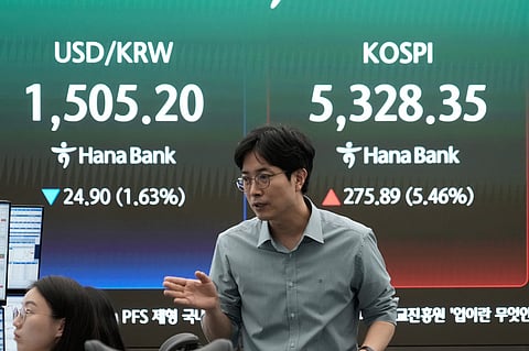 A currency trader reacts near a screen showing the Korea Composite Stock Price Index (KOSPI), right, and the foreign exchange rate between U.S. dollar and South Korean won at the foreign exchange dealing room of the Hana Bank headquarters in Seoul, South Korea, Wednesday, April 1, 2026.