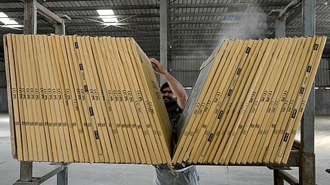 A worker counts a stack of tiles manufactured at a ceramics factory that remains closed amid propane gas supply constraints and a global energy crisis owing to the West Asia war in Morbi on March 25, 2026.